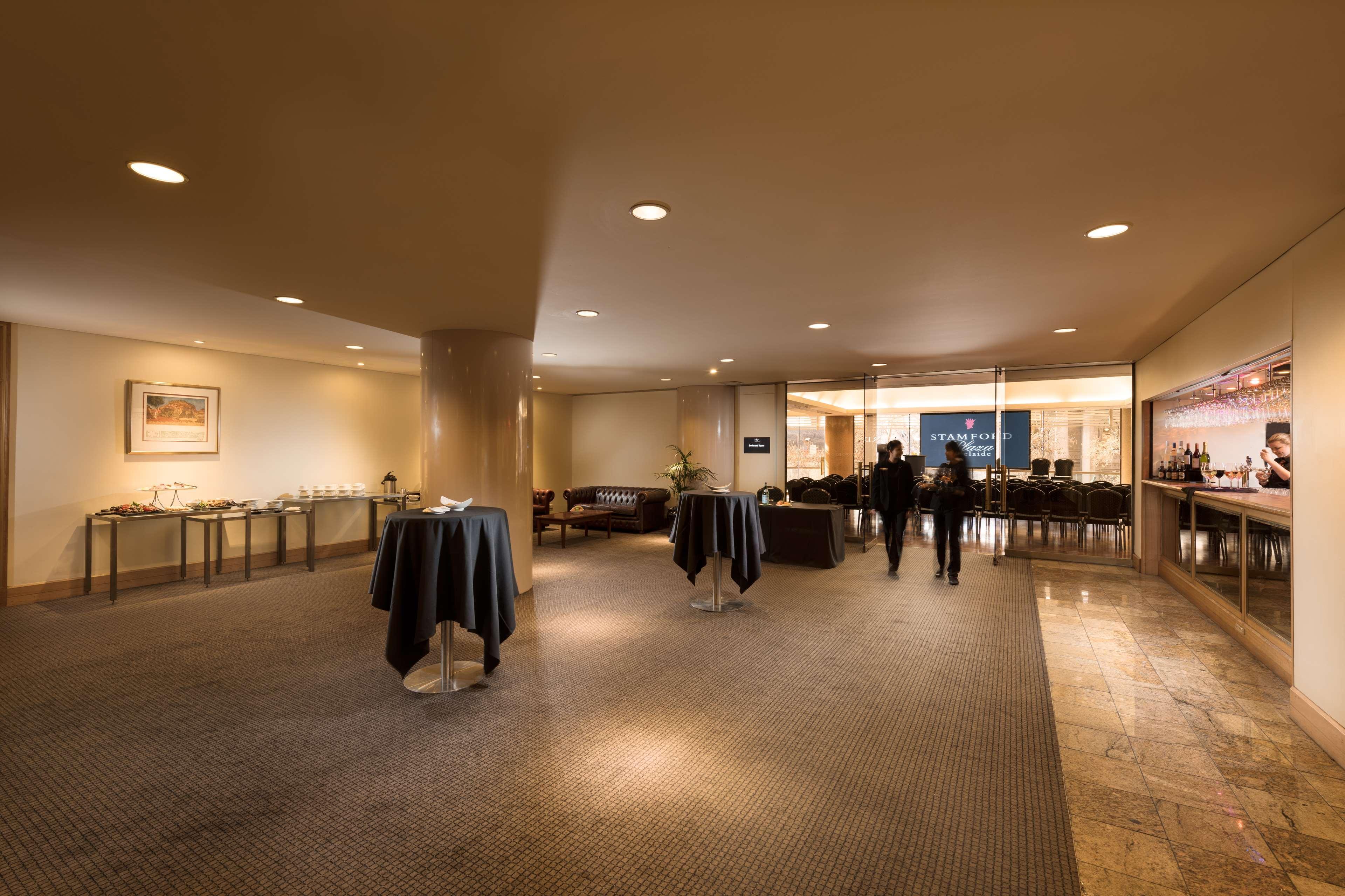 Hotel Stamford Plaza Adelaide Exteriér fotografie The image shows an indoor space that appears to be a lounge or reception area. There are several round tables with dark tablecloths positioned throughout the room. The floor is carpeted, and the lighting is warm and somewhat dim. In the background, t
